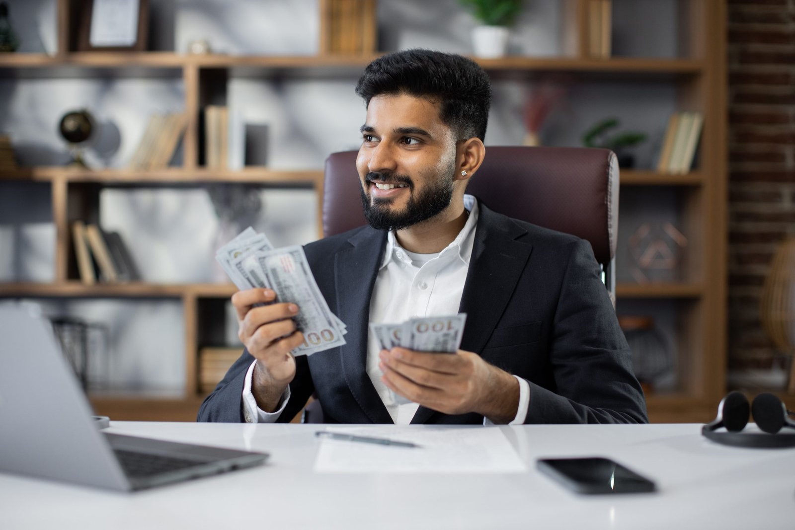 Rich business man working on laptop counting money cash, calculate earnings income profit at office workplace. Professional manager freelancer guy. Business people. Employment, occupation